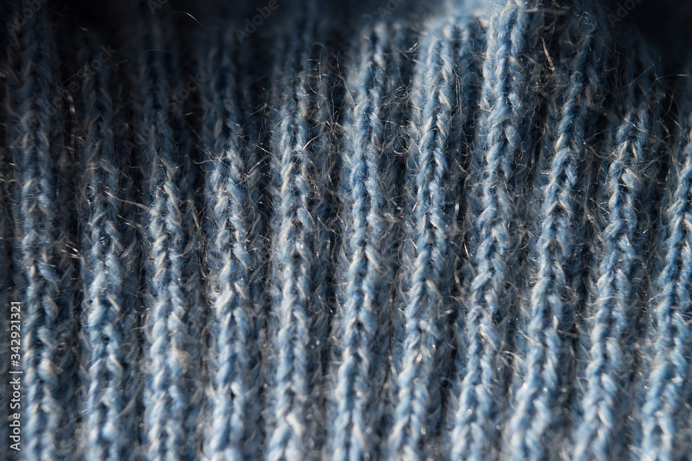 textured knitting pattern with woolen threads of blue color, close-up, top view, knitted lines and patterns
