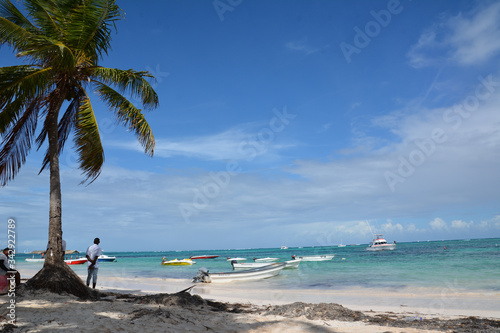 Bavaro, Dominican Republic - January 17, 2018. Beach, white sand, palm trees and boats in the ocean and blue sky.