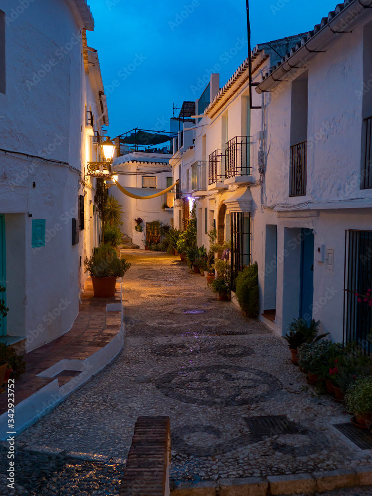 Calle española de Andalucía de la costa del sol amaneciendo llena de macetas y fachadas de cla Calle española de Andalucía de la costa del sol amaneciendo llena de macetas y fachadas de cla