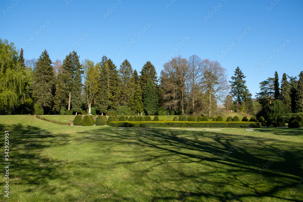 Hamburg/Germany - 4/21/2020: Jesus statue surrounded by a park at the Ohlsdorf cemetery on a sunny day with a bright blue sky. Hamburg/Germany - 4/21/2020: Jesus statue surrounded by a park at the Ohlsdorf cemetery on a sunny day with a bright blue sky.