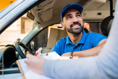 Delivery man in van while customer sign in clipboard.