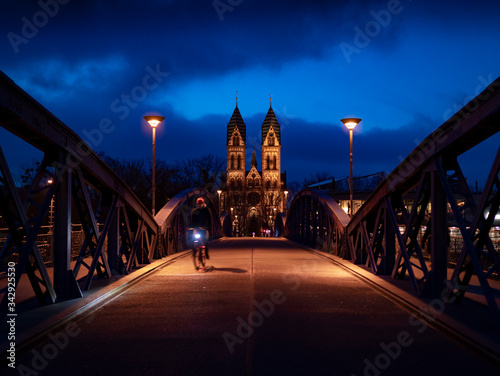 bicicleta cruzando puente por la noche azulada e iglesia al fondo