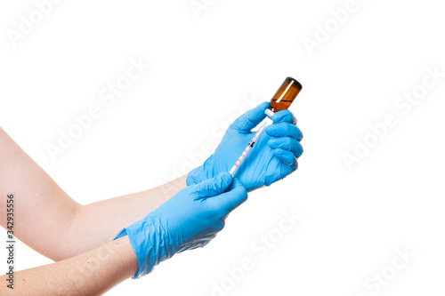 hands in blue medical gloves are holding a glass bottle with a vaccine while typing a drug into an injection syringe, medical theme close up isolated on white background with copy space.