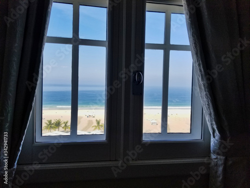 Window with View onto Enticing Empty Beach with Chairs on Sunny Day at Ocean