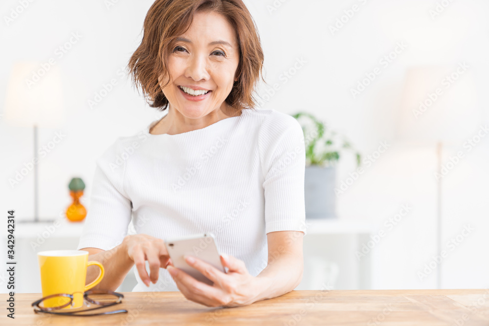 部屋でスマホを見るシニア女性 部屋でスマホを見るシニア女性