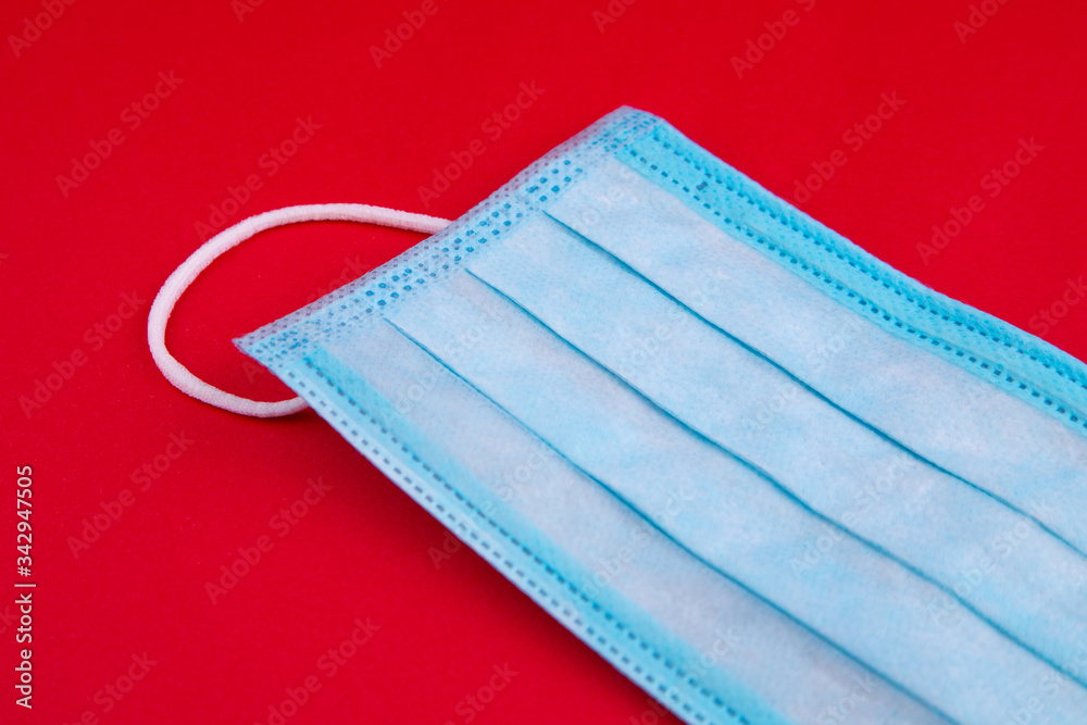 Medical mask. Medical protective masks on red background. Disposable surgical face mask cover the mouth and nose. Healthcare and medical concept. Blue medical disposable face mask, close up on red. Medical mask. Medical protective masks on red background. Disposable surgical face mask cover the mouth and nose. Healthcare and medical concept. Blue medical disposable face mask, close up on red.