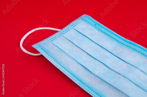 Medical mask. Medical protective masks on red background. Disposable surgical face mask cover the mouth and nose. Healthcare and medical concept. Blue medical disposable face mask, close up on red.