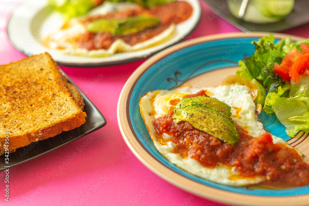 Huevos, recién horneados con una salsa de tomate y una ensalada con aguacate, para una dieta keto o personas fit. Huevos, recién horneados con una salsa de tomate y una ensalada con aguacate, para una dieta keto o personas fit.