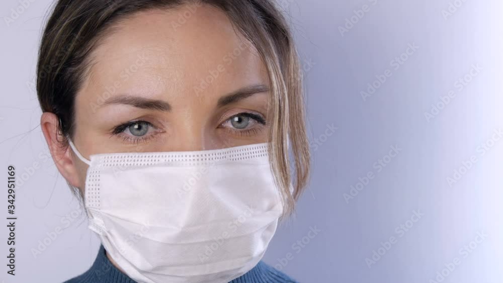 Portrait Beautiful young woman with tousled hair tired eyes in medical mask on a white background close-up view. Nurses, medical staff during epidemic. Health care Coronavirus and medical concept Portrait Beautiful young woman with tousled hair tired eyes in medical mask on a white background close-up view. Nurses, medical staff during epidemic. Health care Coronavirus and medical concept