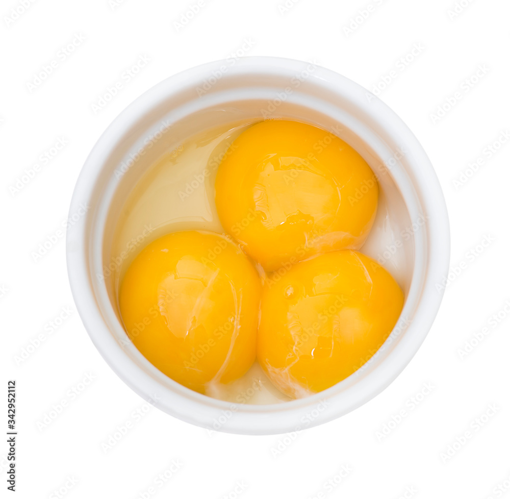 Bright yellow egg yolks in a white bowl on white background