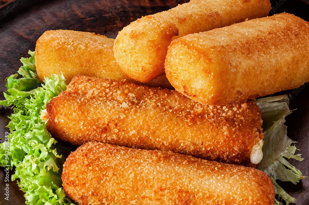 fried suluguni cheese sticks breaded on a lettuce leaf close-up