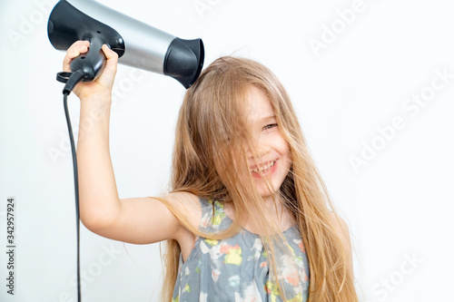 little girl drying her long hair with hair dryer 