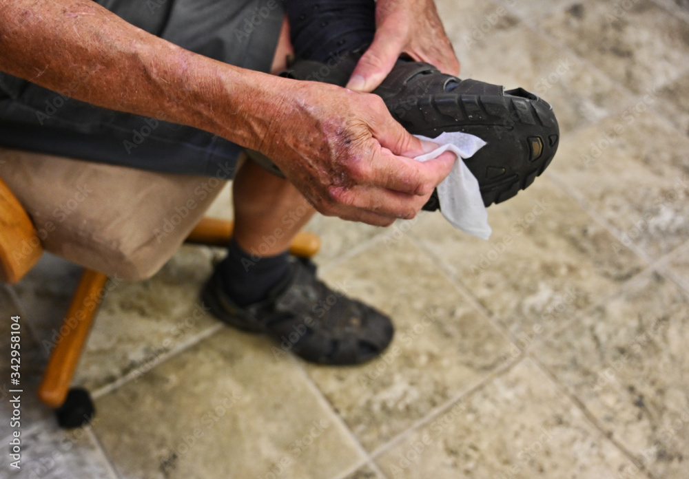 Man Washing Shoe Soles with Sanitizer for Coronavirus Covid-19 Protection
