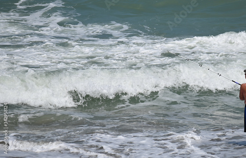Man Fishing at Ocean Beach Surf with Social Distancing for Coronavirus Covid-19