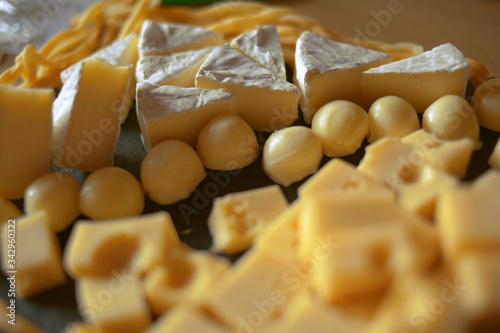 Cheese cutting, cheeses of different types on a black background, soy. Camembert, hard cheese, pigtail cheese, promezan, cheese balls, cheese with holes. Cheese department, to wine.