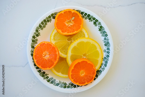 orange and lemon slices on a saucer set on white marble