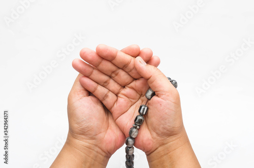 Hand holding muslim beads rosary or tasbih isolated on white background.