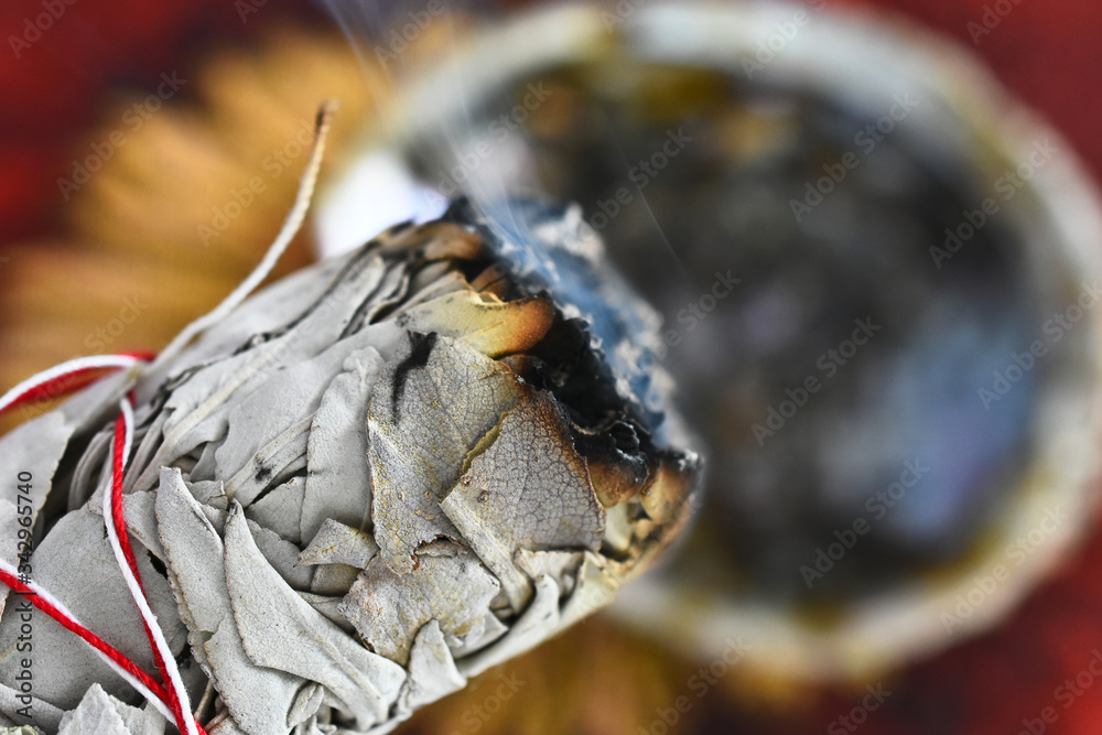 A close up image of a hand holding a burning white sage smudge stick. A close up image of a hand holding a burning white sage smudge stick.