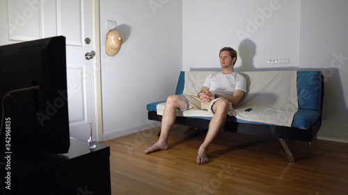Young Man Sitting on Couch and Watching TV Alone at Night