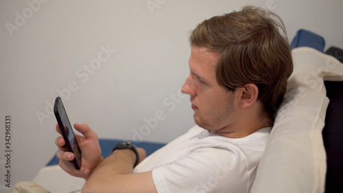Young Man Mindlessly Scrolling Social Media on Smartphone