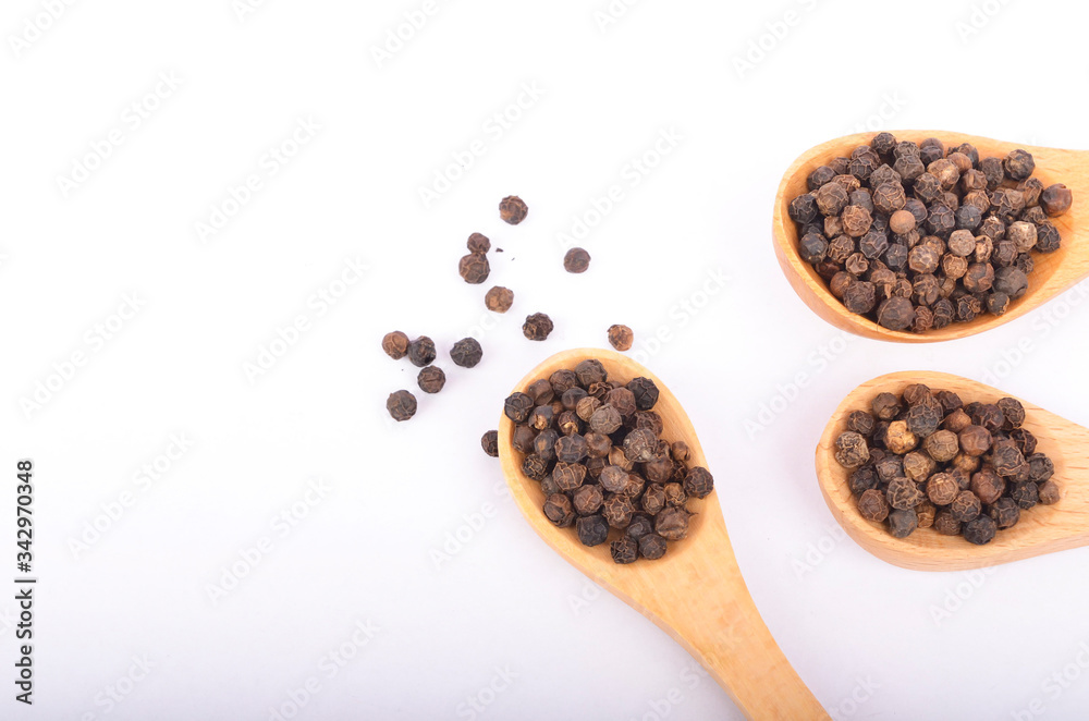 Black peppers on wooden spoon on white background. Black peppers on wooden spoon on white background.