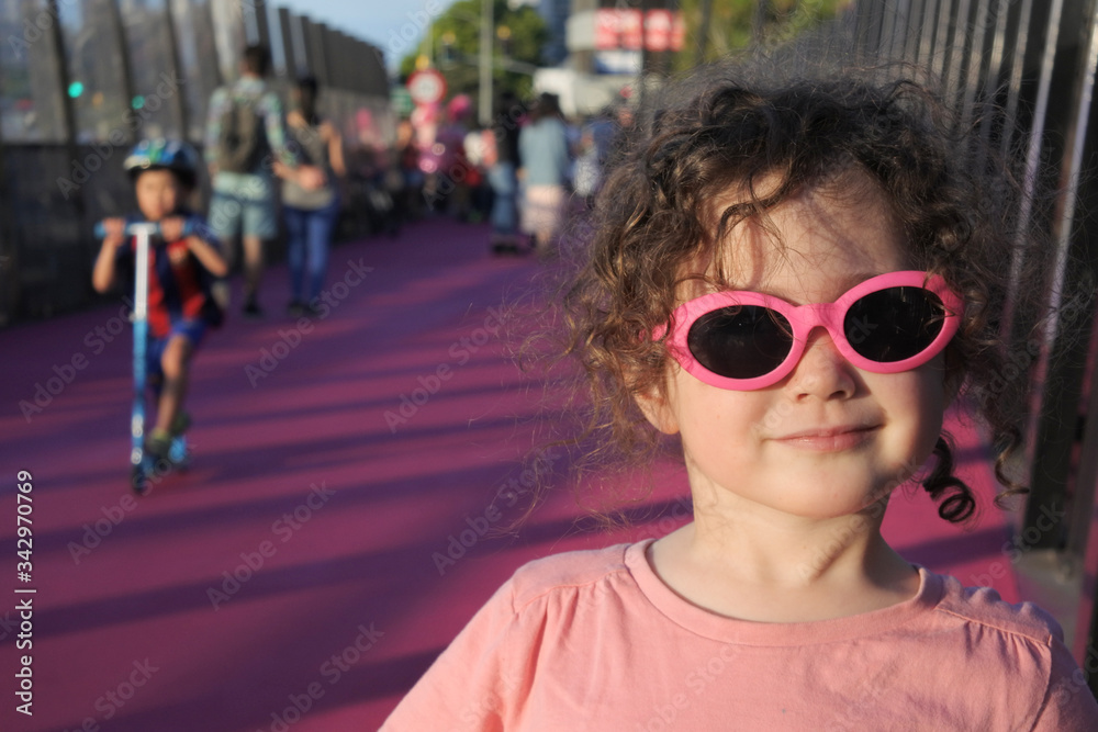 Young girl wearing sunglasses in urban city street looking at camera Young girl wearing sunglasses in urban city street looking at camera