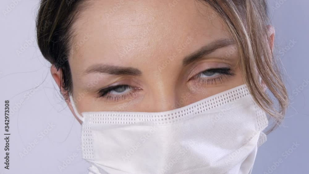 Portrait Beautiful young woman with tousled hair tired eyes in medical mask on a white background close-up view. Nurses, medical staff during epidemic. Health care Coronavirus and medical concept Portrait Beautiful young woman with tousled hair tired eyes in medical mask on a white background close-up view. Nurses, medical staff during epidemic. Health care Coronavirus and medical concept