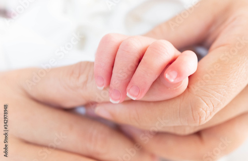 Hand of sleeping new born infant baby in the hand of mother close up on the bed