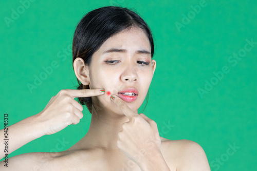 Wallpaper Mural Worried stressed young Asian woman touching her skin face with finger and looking acne problem over green isolated background. Beauty skin care concept. Torontodigital.ca