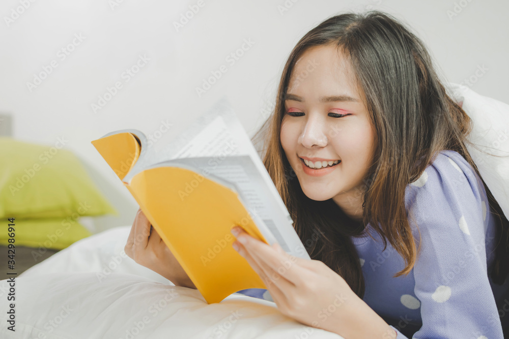 Stay Home. happy young asian pretty woman in casual clothing lying on bed and enjoying reading a book at morning in bedroom at home, joyful weekend, student, leisure, quarantine and lifestyle concept Stay Home. happy young asian pretty woman in casual clothing lying on bed and enjoying reading a book at morning in bedroom at home, joyful weekend, student, leisure, quarantine and lifestyle concept