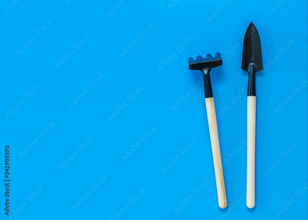 Garden rake and shovel with wooden handles on a blue background. Garden rake and shovel with wooden handles on a blue background.