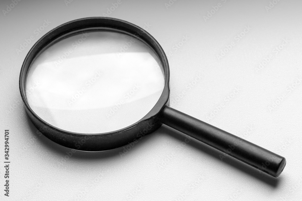 A black magnifier lies on a white windowsill. A black magnifier lies on a white windowsill.