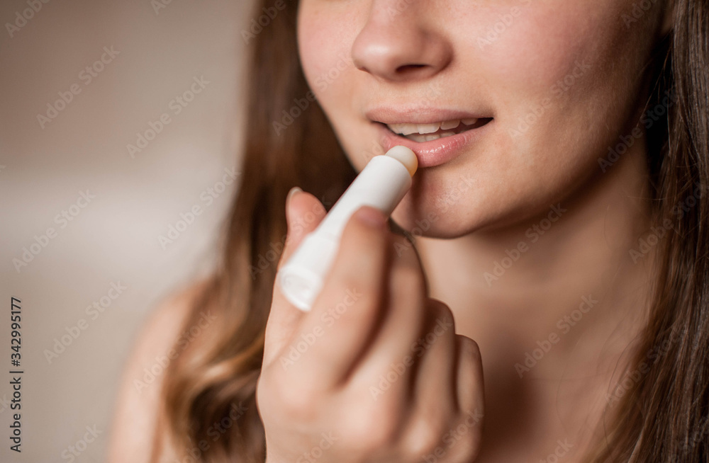a brunette girl without makeup with problematic skin with a bandage with ears on her head naked wrapped in a towel after a bath doing Spa treatments applies lip balm to lips moisturizes a brunette girl without makeup with problematic skin with a bandage with ears on her head naked wrapped in a towel after a bath doing Spa treatments applies lip balm to lips moisturizes