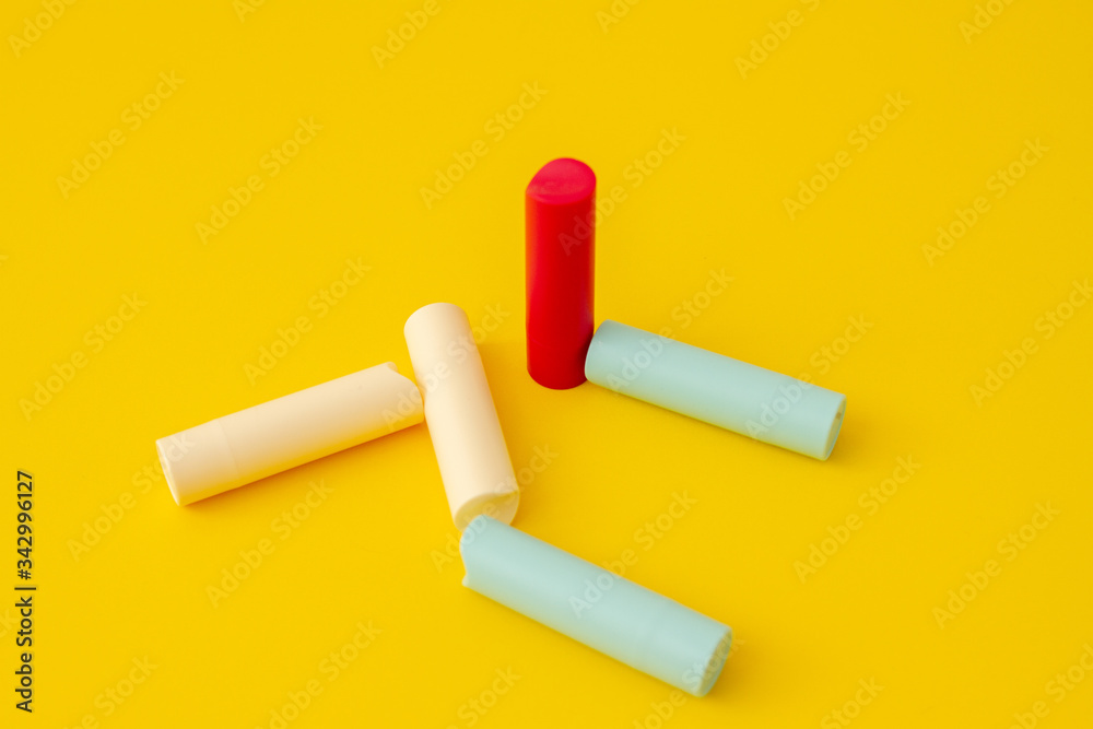 Multi-colored tubes of lipstick on a yellow background in an abstract form and shape Multi-colored tubes of lipstick on a yellow background in an abstract form and shape