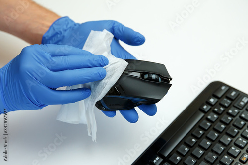 Covid-19 sanitizing office space wiping corona virus cleaning and disinfection of your workspace. Disinfecting wipes to wipe surface of desk, keyboard, mouse at office.