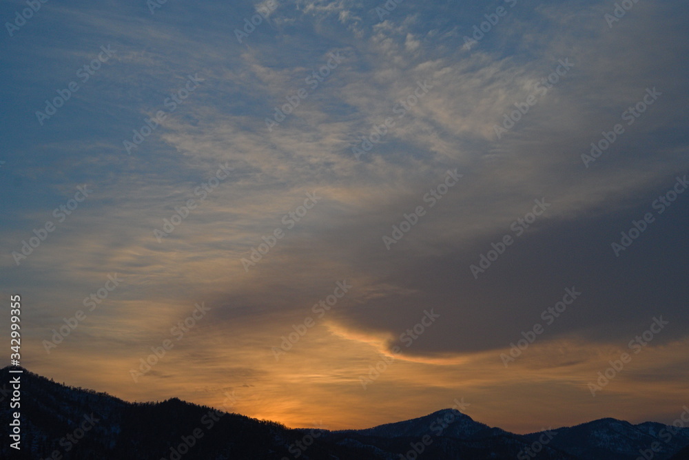 夕暮れの空の雲と山並みのシルエットの風景。