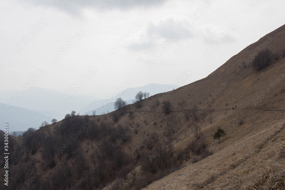 Trekking path crossing slope with dry grass and mountains on background. Trekking path crossing slope with dry grass and mountains on background.