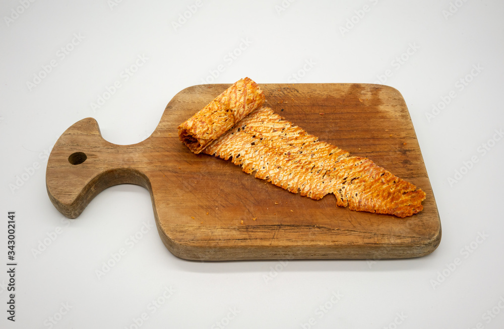 Spicy dried and rolled squid on wooden cutting board isolated on white. Fine chili seasoning seafood snacks. Spicy dried and rolled squid on wooden cutting board isolated on white. Fine chili seasoning seafood snacks.