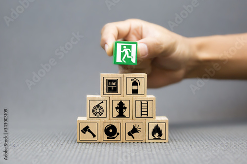 Photo Close-up hand choose a wooden toy blocks with fire exit icon for fire safety protection concepts