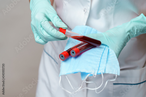 medical doctor nurse woman wearing latex gloves - holding virus blood test and protective mask