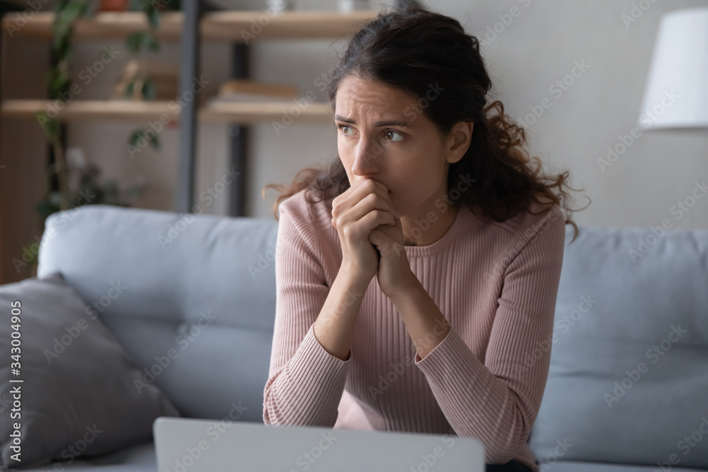 Nervous young woman sitting on sofa, worrying about bad news, received by email on laptop. Stressed businesswoman thinking of crisis challenges, feeling desperate or unsure, stack with hard decision. Nervous young woman sitting on sofa, worrying about bad news, received by email on laptop. Stressed businesswoman thinking of crisis challenges, feeling desperate or unsure, stack with hard decision.