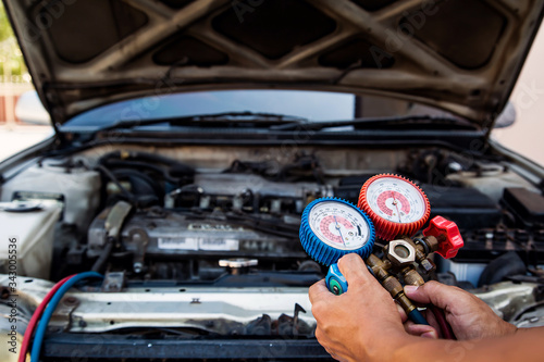 Auto mechanic using measuring equipment for filling car air conditioners checking. Concepts of car Repair service and car insurance.