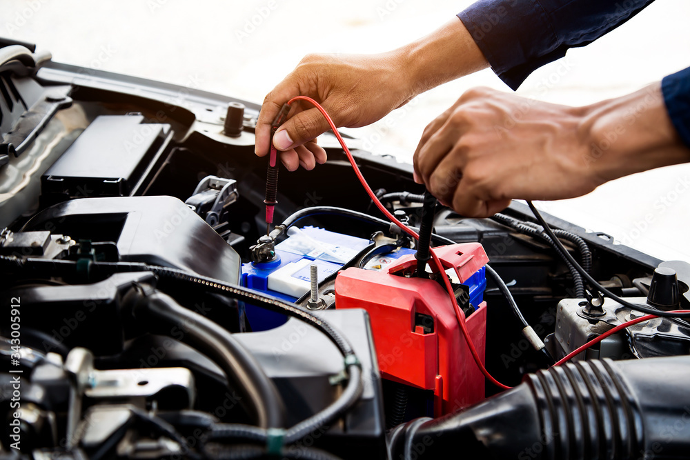 Auto mechanic using measuring equipment for checking car battery. Concepts of car Repair service and car insurance. Auto mechanic using measuring equipment for checking car battery. Concepts of car Repair service and car insurance.