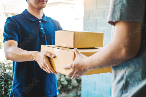 Delivery concept Asian Man hand accepting a delivery boxes from professional deliveryman at home photo
