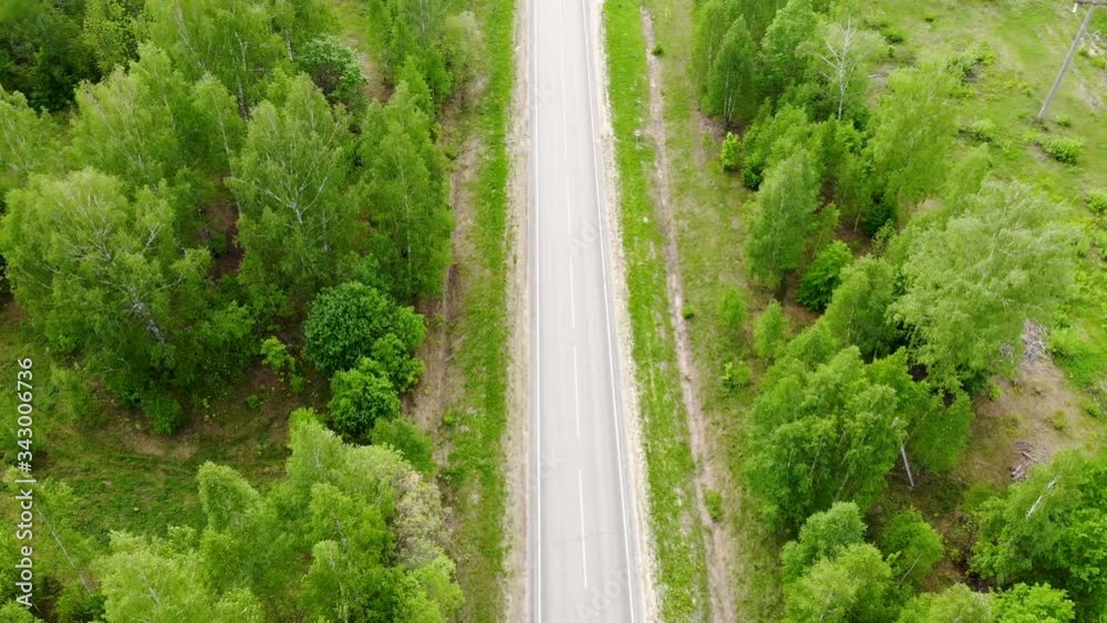 Aerial drone flight over the highway on which a truck passes. The freeway is surrounded by nature and a mixed forest. Taken outdoor in the summer day Aerial drone flight over the highway on which a truck passes. The freeway is surrounded by nature and a mixed forest. Taken outdoor in the summer day