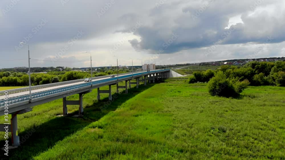 Aerial drone flight over the flyover, on which cars and trucks pass. The bridge is part of the highway. Taken on the outskirts of the city in summer in cloudy weather