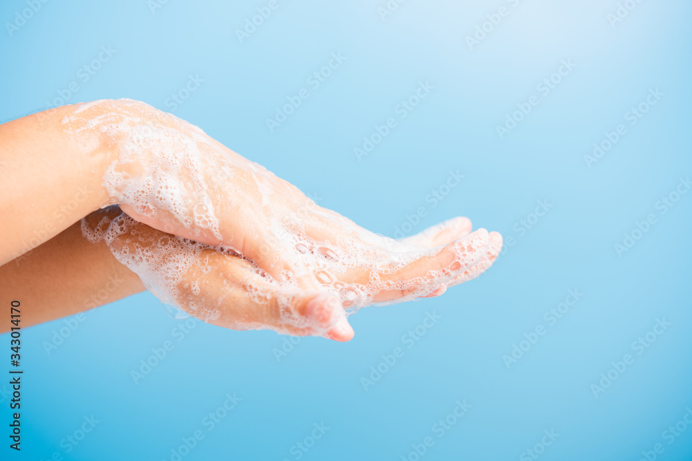Closeup body care Asian young woman washing hands with soap have foam, hygiene prevention COVID-19 or coronavirus protection concept, isolated on blue background Closeup body care Asian young woman washing hands with soap have foam, hygiene prevention COVID-19 or coronavirus protection concept, isolated on blue background