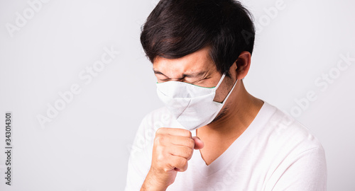 Asian handsome Man wearing surgical hygienic protective cloth face mask against coronavirus he sneeze hand close mouth  studio shot isolated white background  COVID-19 medical concept