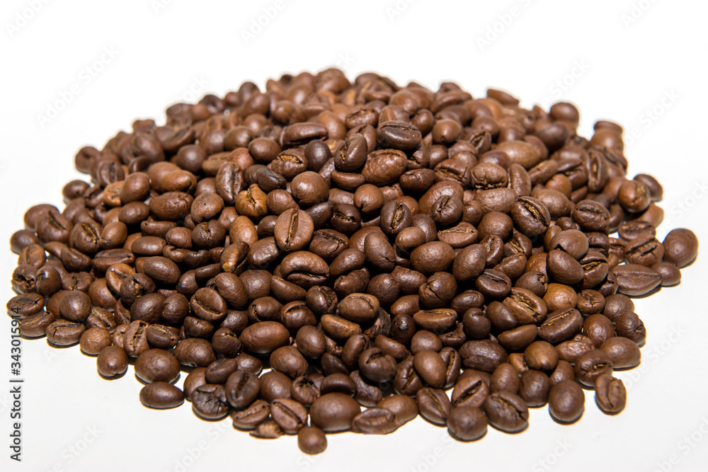 a pile of freshly roasted coffee beans isolated on a white background.