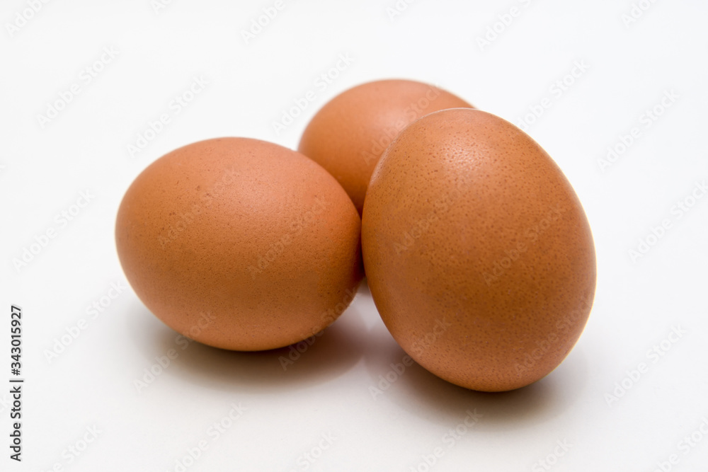 three brown eggs on a white background close up three brown eggs on a white background close up